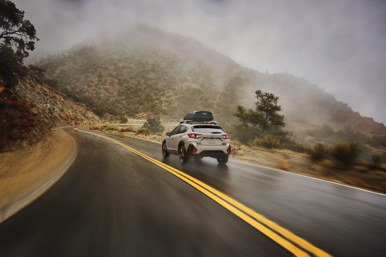 2026 Subaru Crosstrek Hybrid driving along a wet road
