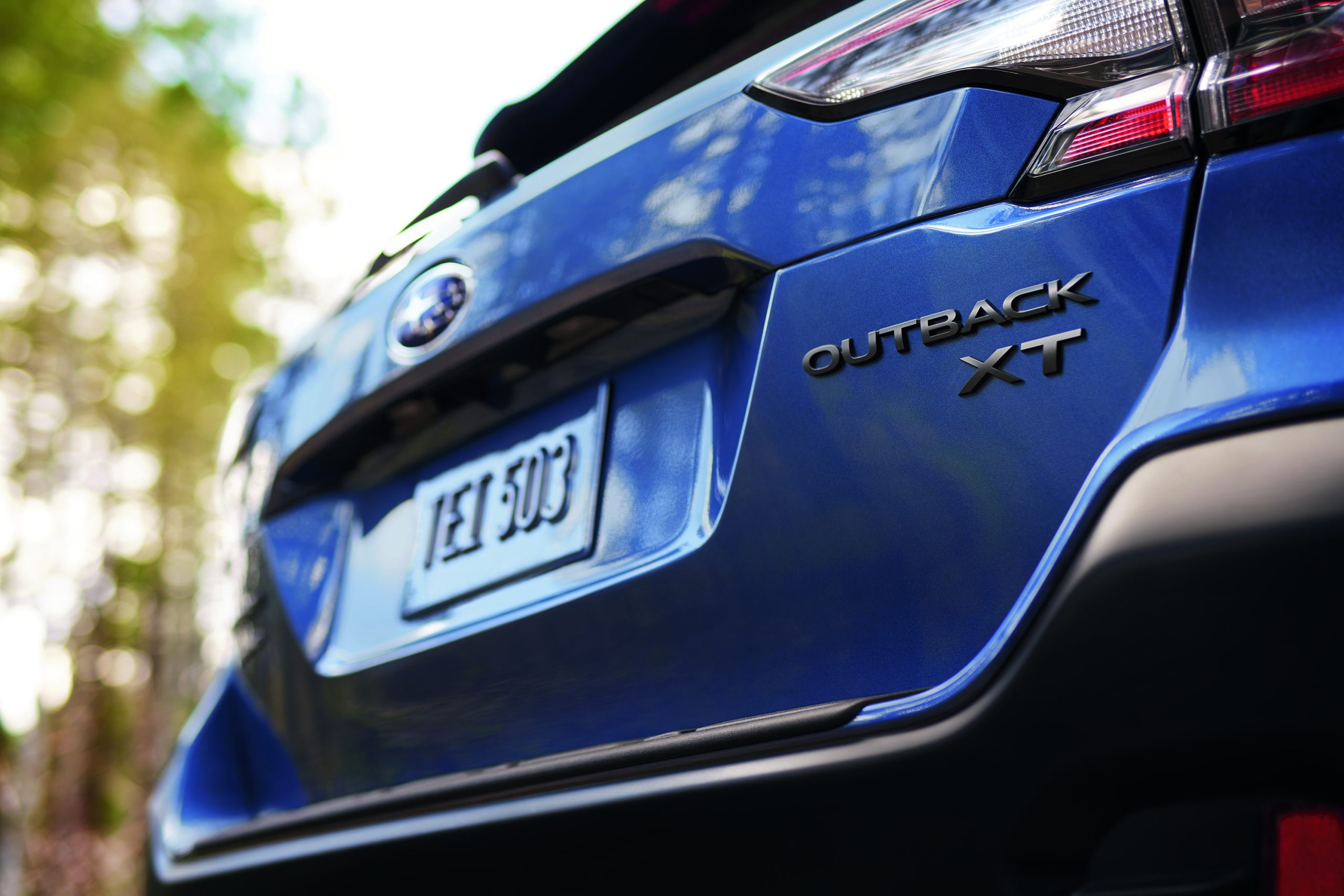 A low-angle photo of the back of a blue Subaru Outback